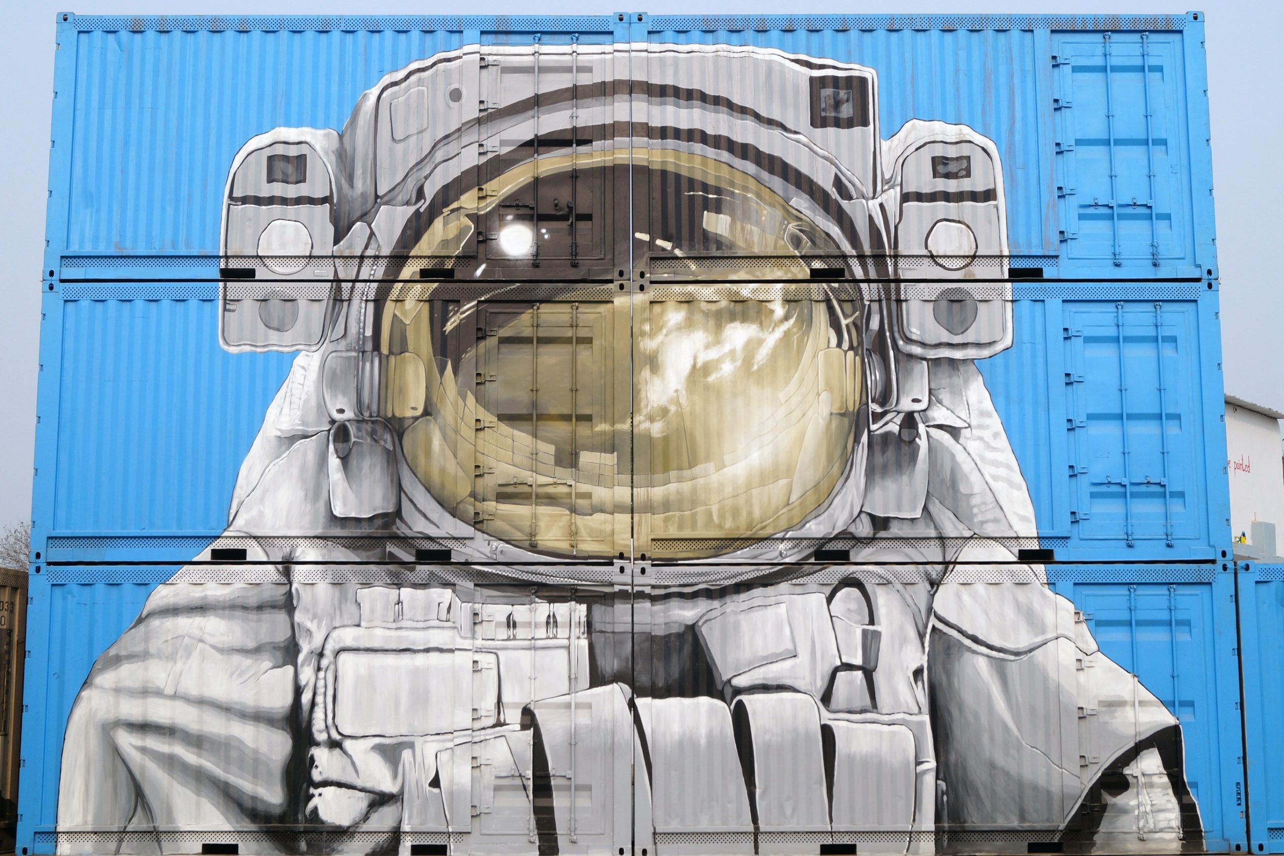 Astronaut mural on stacked blue shipping crates, Coachella Valley art scene.