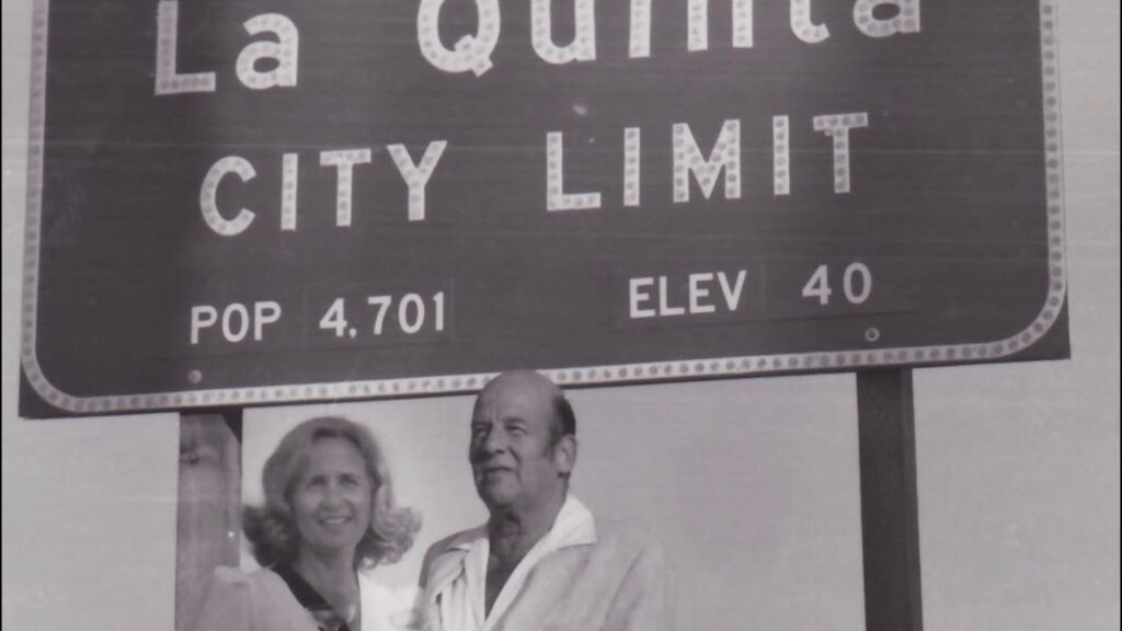 Fred and Kay Wolff historic photo taken. in front of a city limit sign that has the population of La Quinta, CA at 4,701.